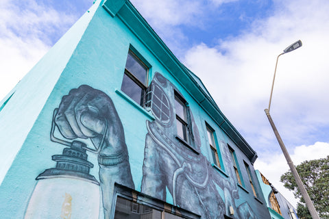 Image of a big aqua blue building with a mural painting, located in New Plymouth, New Zealand