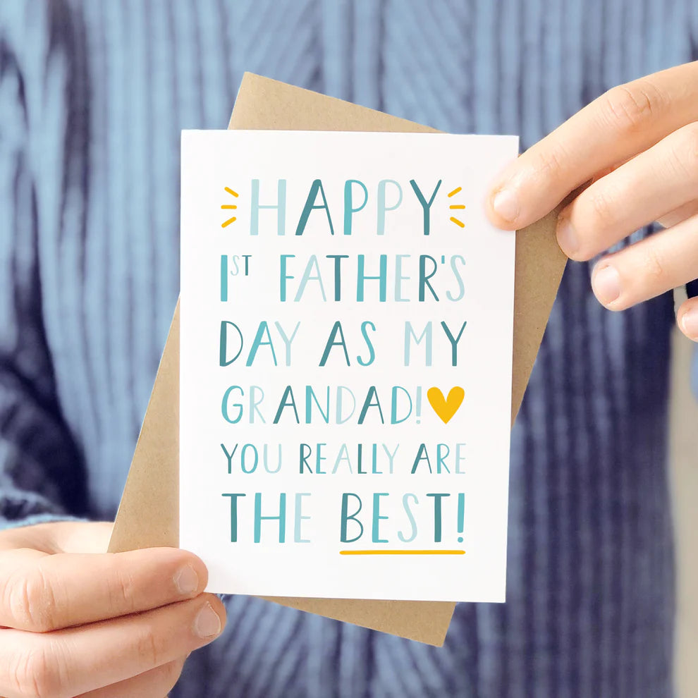 1st Father's day as a grandad greeting card held by a man in a knitted jumper.