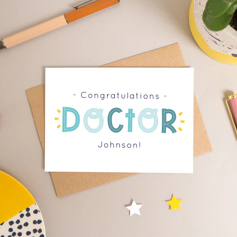 Personalised Doctor card for graduation or doctorate photographed on a beige background.