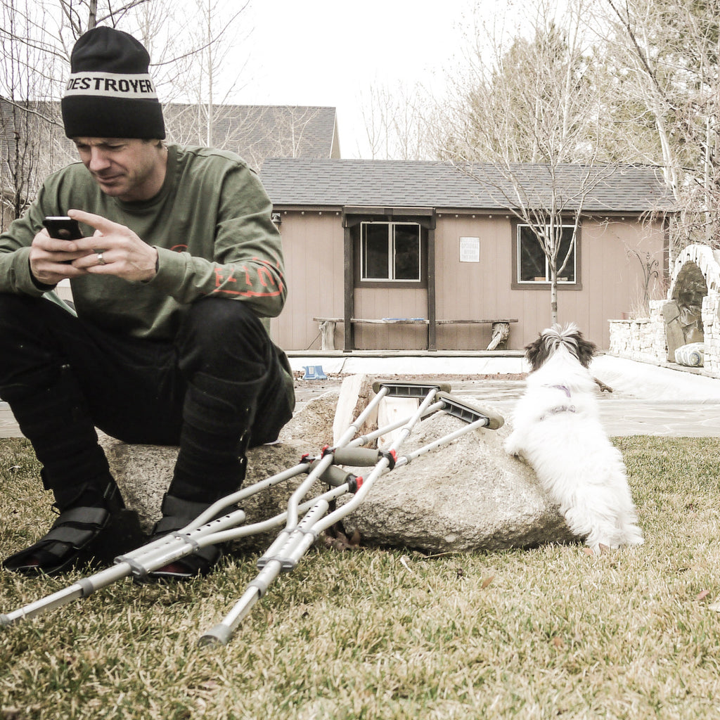Jeremy Jones sitting in his backyard with his crutches and his dog Mozzy.
