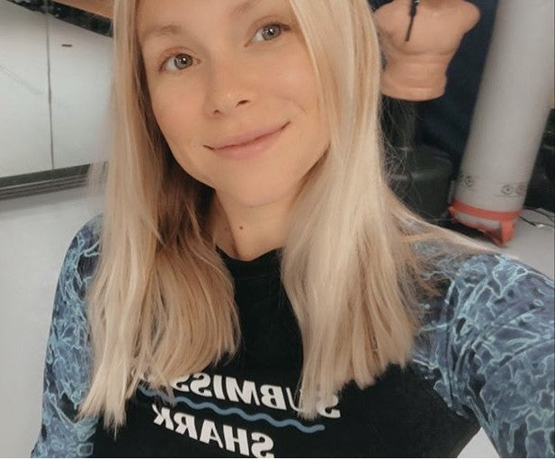 A happy blonde BJJ girl in a Submission Shark jiu jitsu rash guard