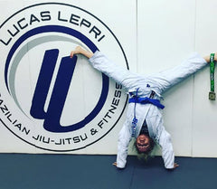 Cheryl Mongeon doing a handstand in a white BJJ gi at Lucas Lepri Academy