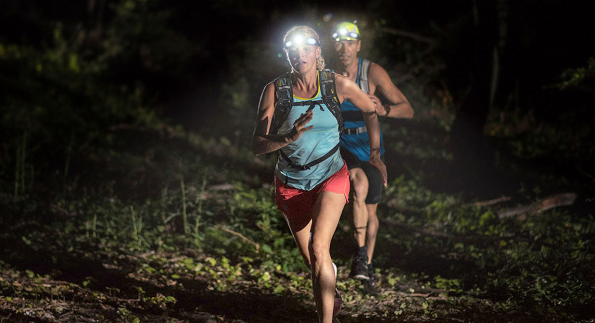 Close up lifestyle image of a man and woman out in the woods backpacking/hiking with Headlamp 3.0s on.