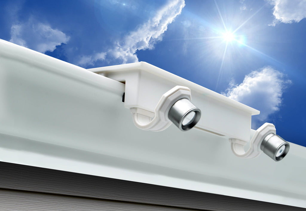 EZ Home Security Solar FLEXIT Gutter Spotlight mounted on a white gutter with a sunny/partly cloudy sky in the background