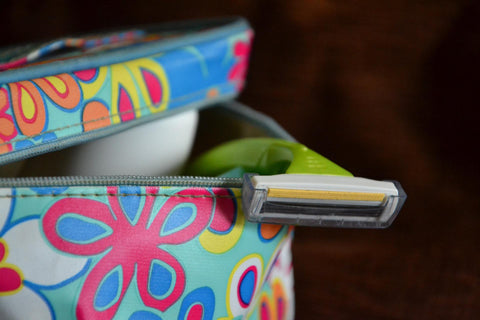 Close up of a cosmetics toiletries bag with a shaving razor hanging out