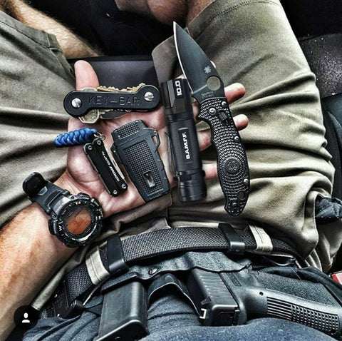 pov shot looking down at a lap full of tactical equipment including pistol clip watch knife bamff tactical flashlight and more