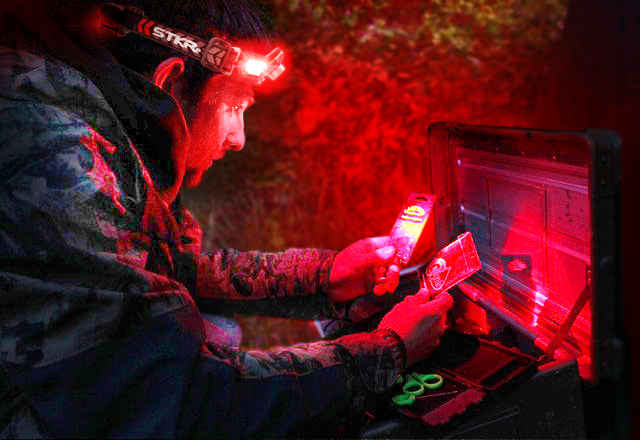 fisherman looking thru tackle box using a flexit headlamp pro red lighting mode by STKR Concepts