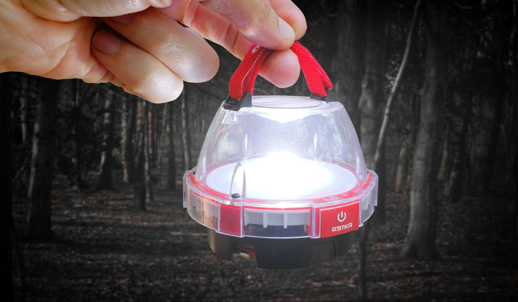 illumidome mini lantern by STKR held up by a hand forest tress in bg