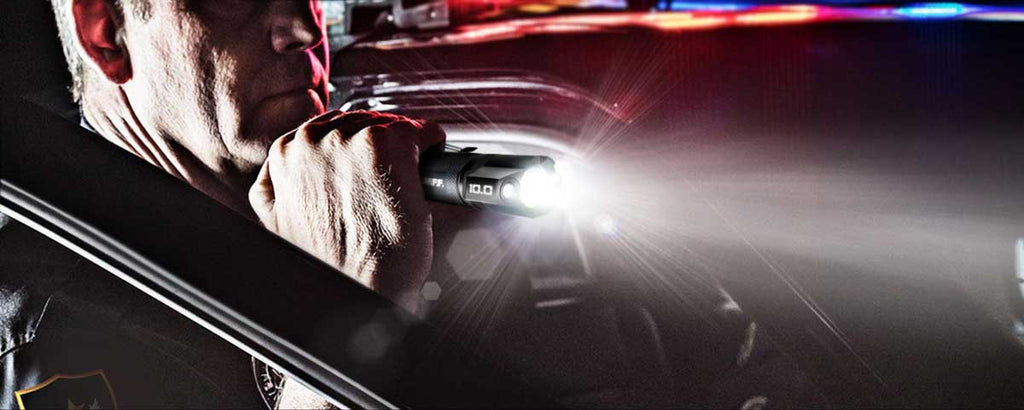 Oficial de policía usando un automóvil como cubierta iluminando la noche con una linterna táctica BAMFF