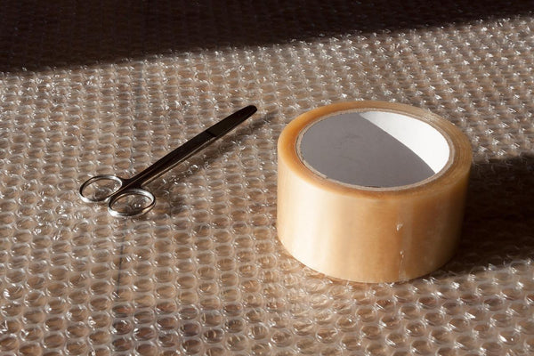 scissor and packing tape sitting on bubble wrap