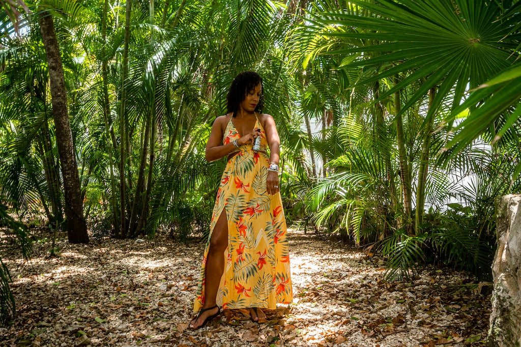 Woman in yellow dress applies bug spray to her arm in a forest in the summer