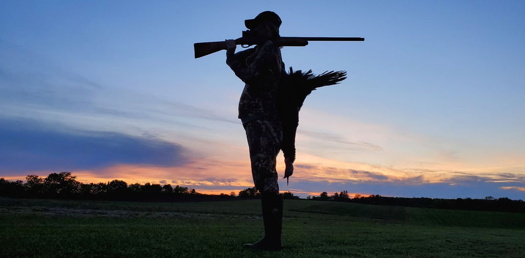woman bird hunting holding a gun in the sunset 