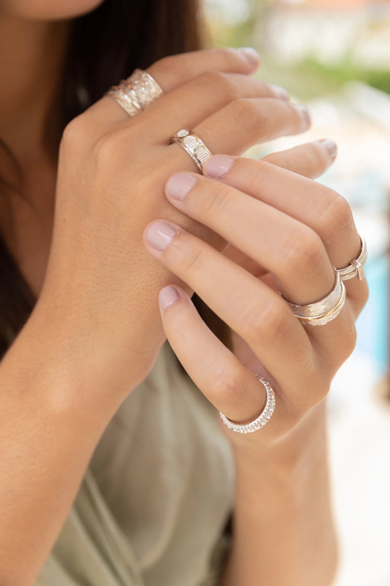 Close-up of hands wearing textured silver spinner rings designed for stress relief