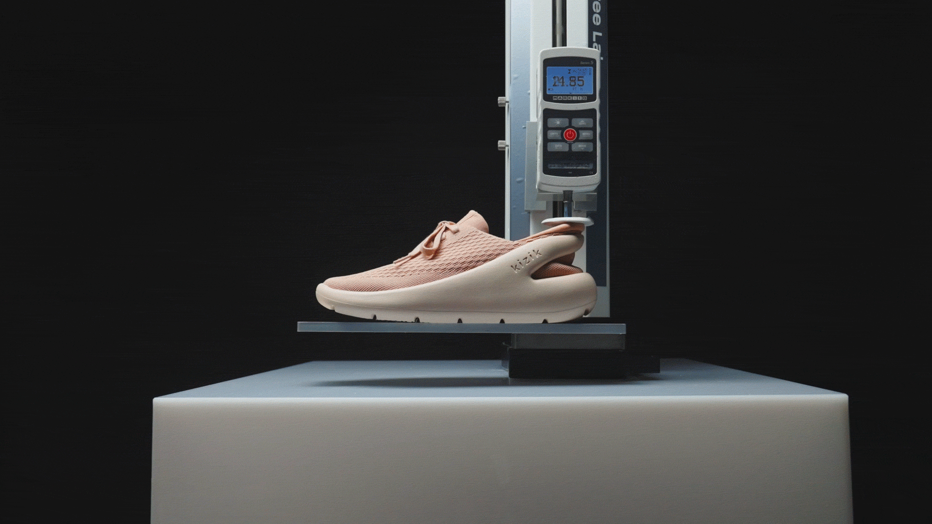 Pink shoe on a scale with digital display, black background.