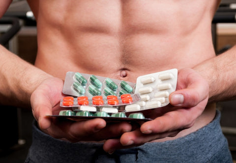 close-up shot of a muscle builder holding several pills