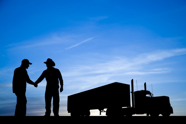 Two men shaking hands , near a truck 