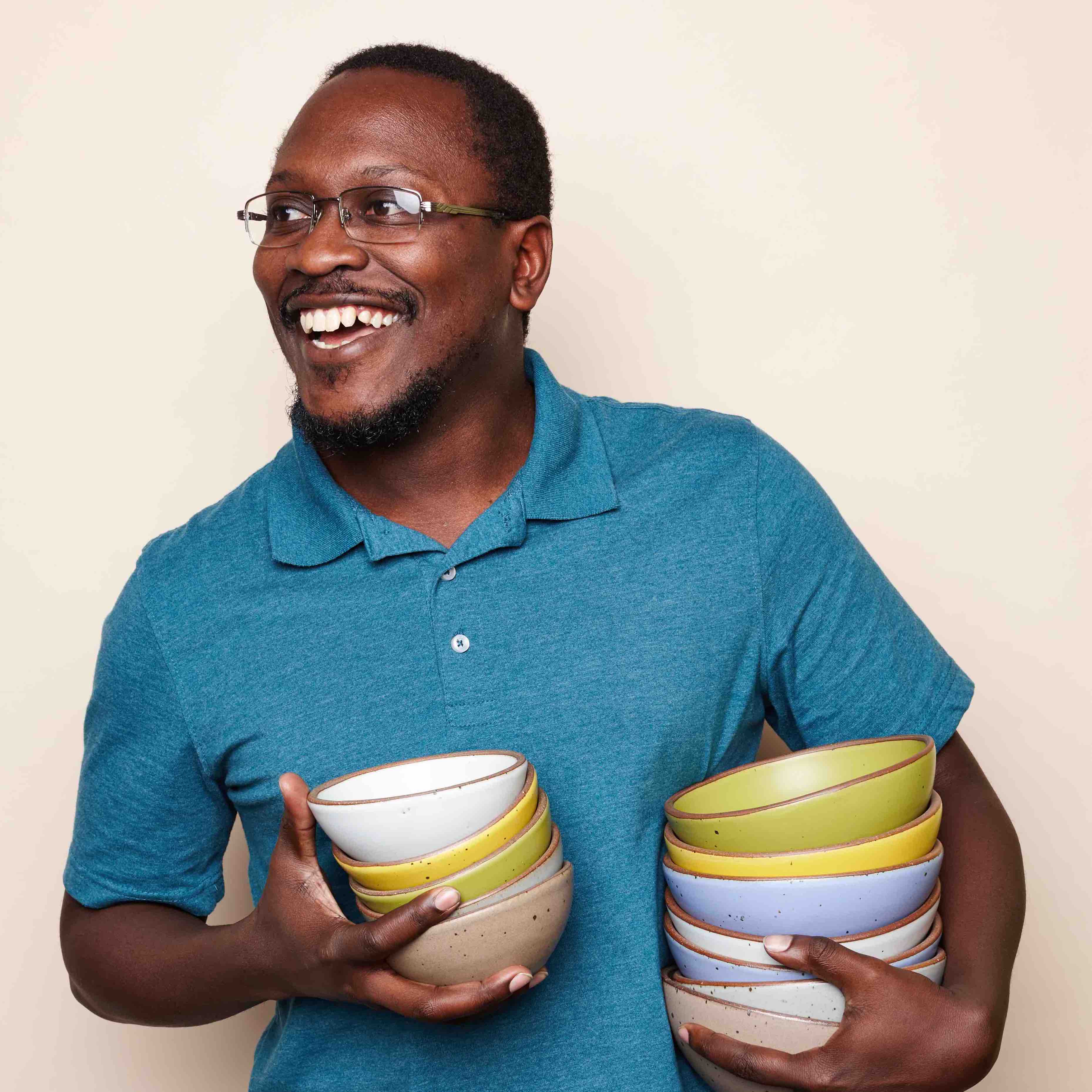 A happy member of the East Fork team holding colorful bowls.