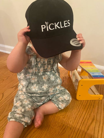 Baby girl with black baseball cap covering her head