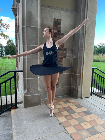 Young ballerina posing while wearing a black tank top and skirt