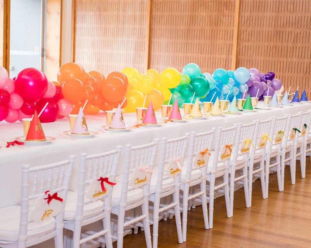 Jayda’s 5th Unicorn Party: Kids table with rainbow balloon runner and rainbow party decorations