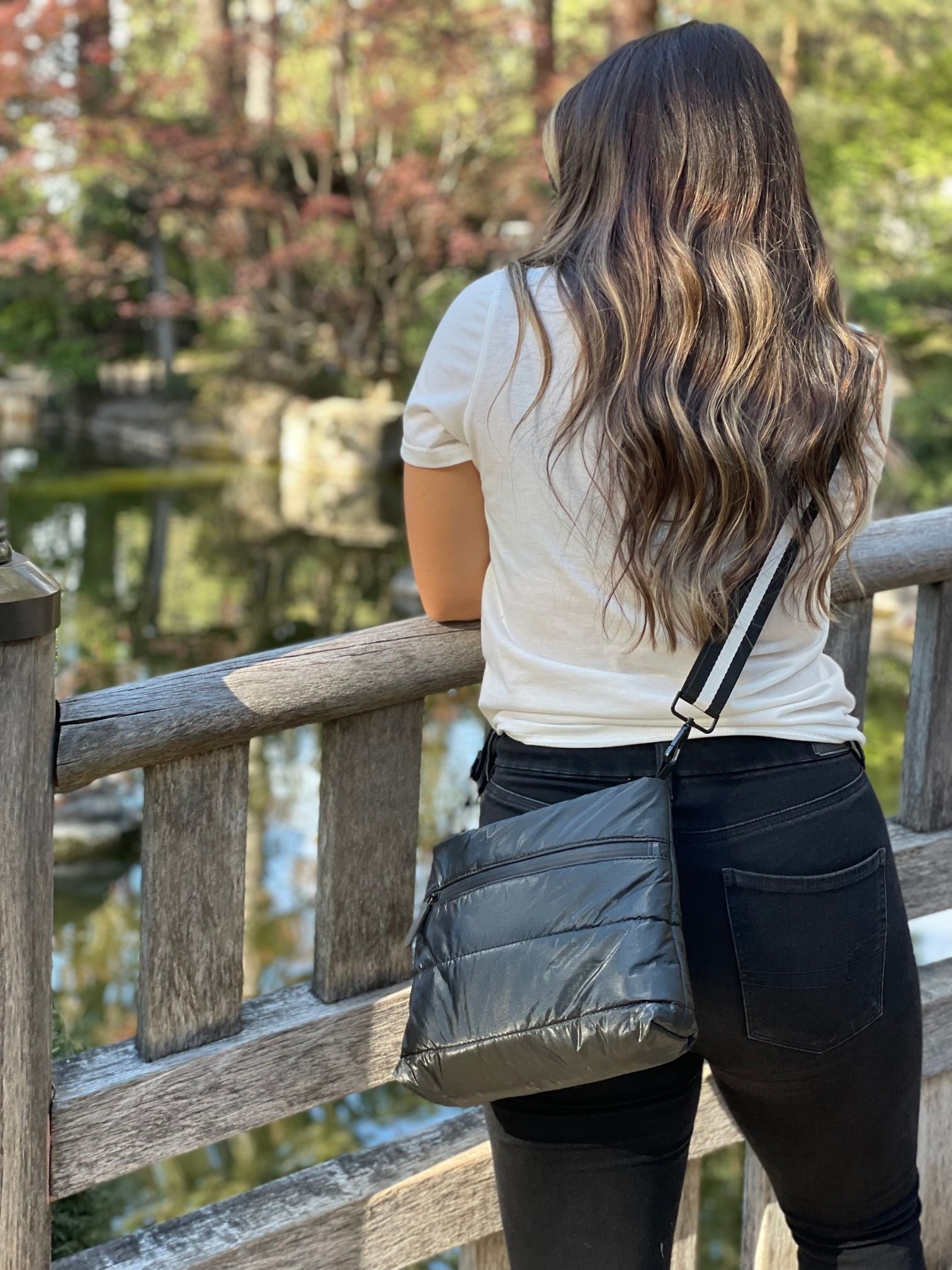 Woman in a white blouse wearing a shimmer black puffer crossbody purse