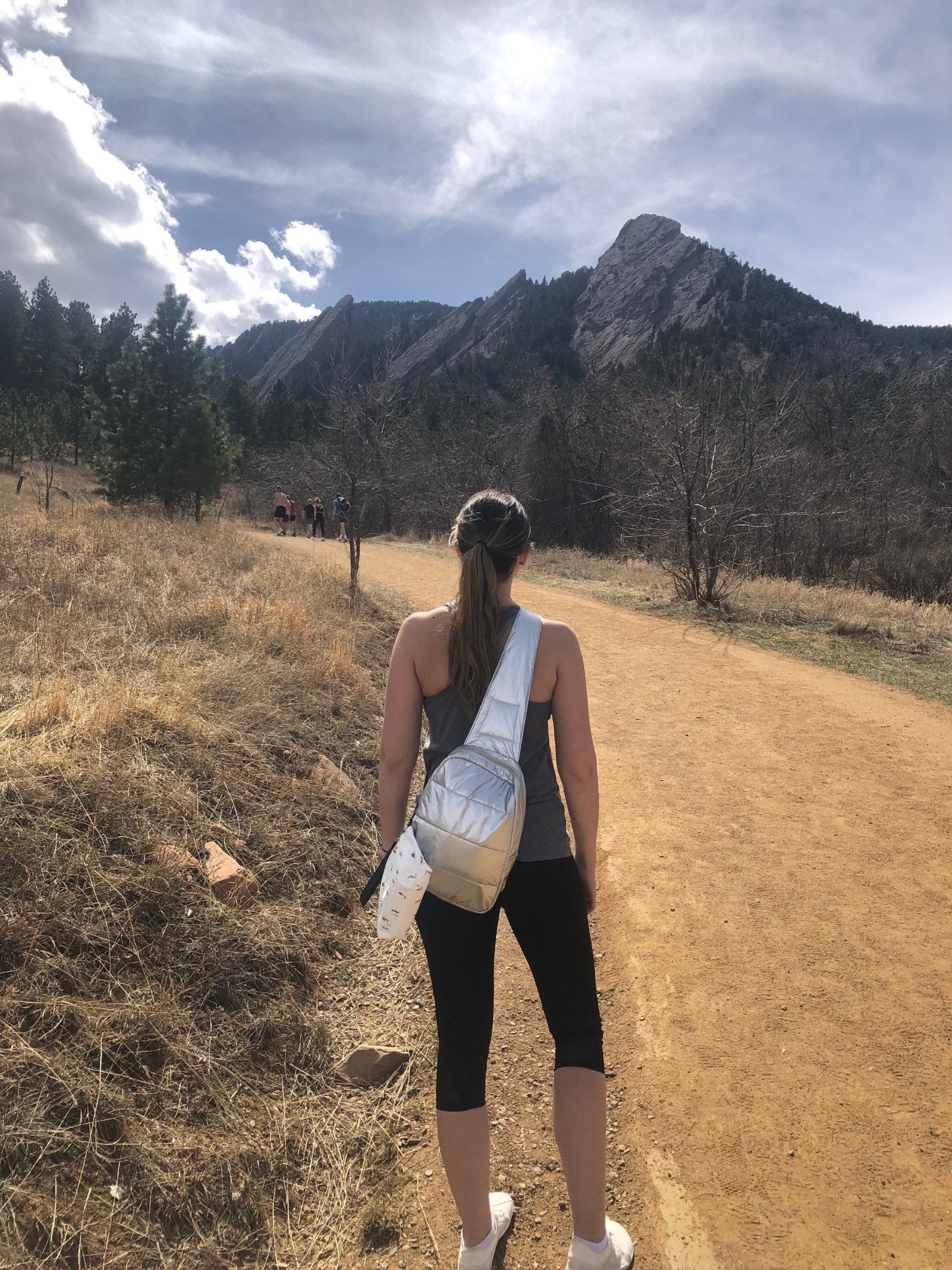 Woman hiking on a mountain wearing a silver crossbody backpack