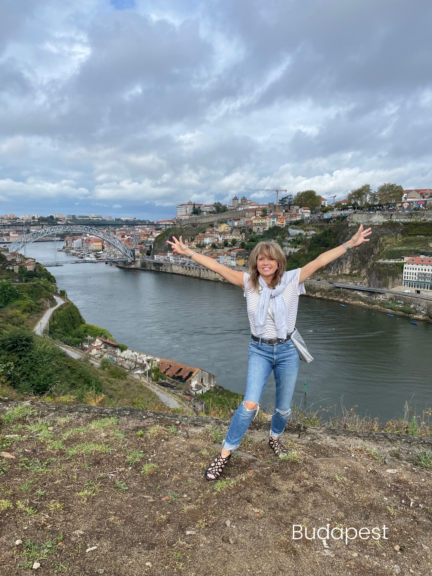 Woman wearing a crossbody purse in Budapest with arms open