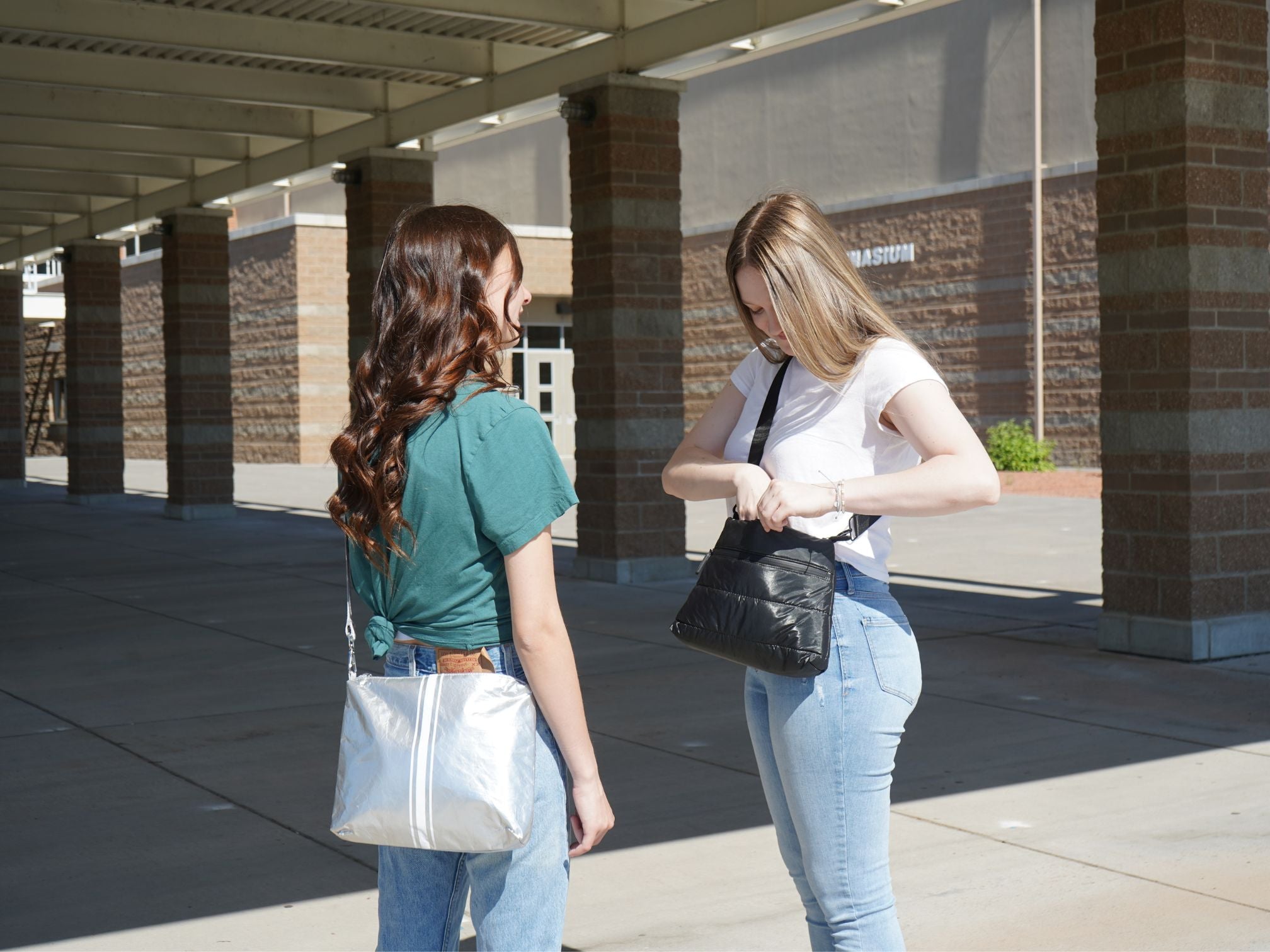 Two young adults in front of school wearing crossbody purses