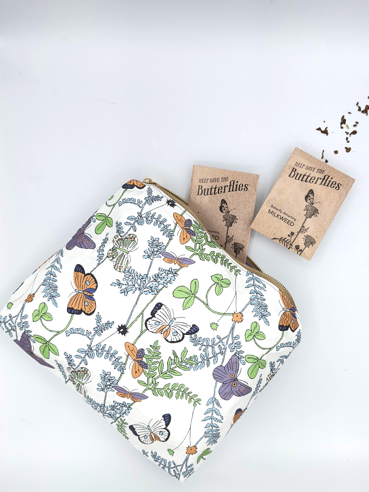 White Zipper Pouch with monarch butterfly pattern and milkweed seeds packets inside