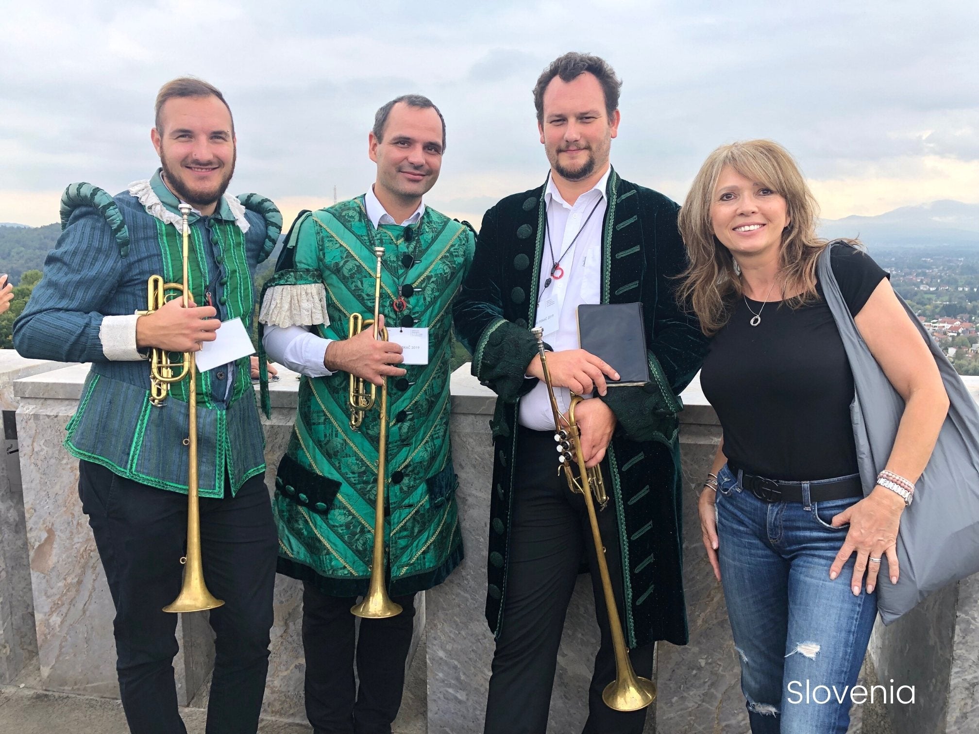 Woman in Slovenia next to three men in uniform holding trumpets