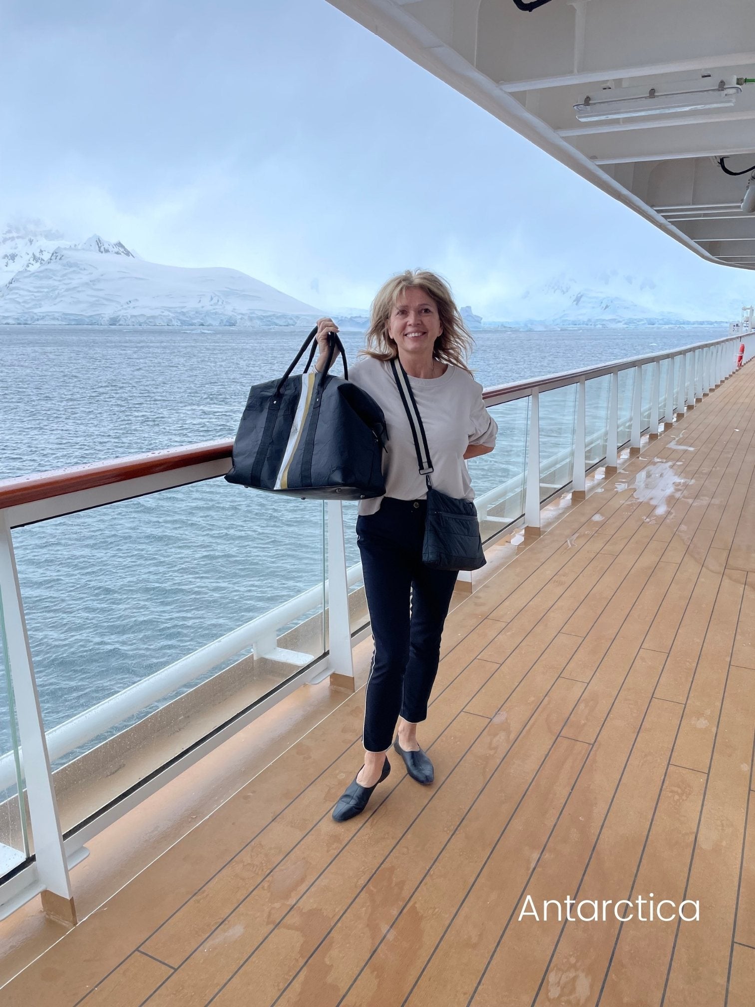 Woman in Antarctica on a cruise ship holding black weekender bag