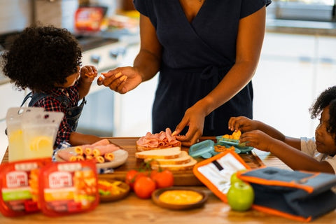 a woman preparing food for her two children