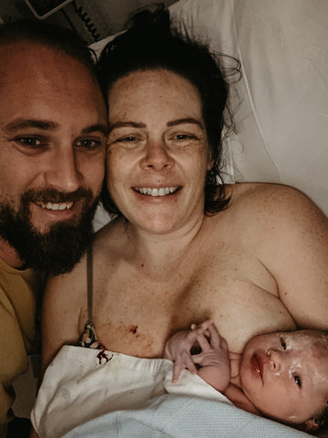 Mum and Dad smiling after a natural birth using a TENS machine with newborn baby in hospital