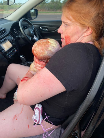 woman holds newborn in the car after giving birth