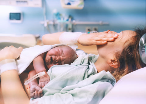 Woman wipes tears after birth with cascade of interventions in hospital