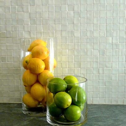 Two glass fruit bowls in kitchen displaying yellow lemons and green limes with a white textured tiled on accent wall in the background. Interior design blog about our tips on bringing your kitchen to life without spending too much money. Written by vintage-etc in Cape Town. We make custom made & bespoke tables, benches, free-standing kitchen islands, desks, media units & wardrobes in our Cape Town & Johannesburg workshops – using Oak, Oregon, Ash, Beech, Birch Ply & Meranti. We also sell imported furniture, provide design consulting services & make soft furnishings e.g. sofas & upholstered chairs in linen, velvet & stain resistant fabric.