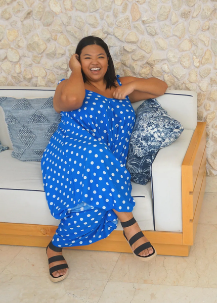A plus size woman wearing a harem jumpsuit sitted in a chair