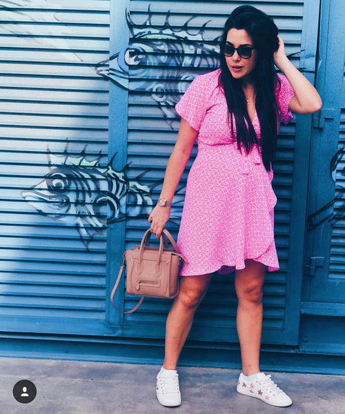 A woman wearing a pink mini maternity dress from Neonstar standing infron t of a house garage in dubai