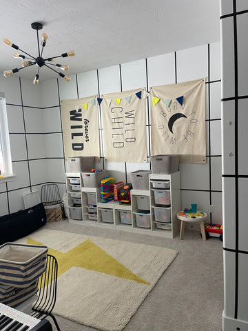 kids playroom with black and white grid walls, 3 canvas flags hanging on the wall, and a lightning bolt rug