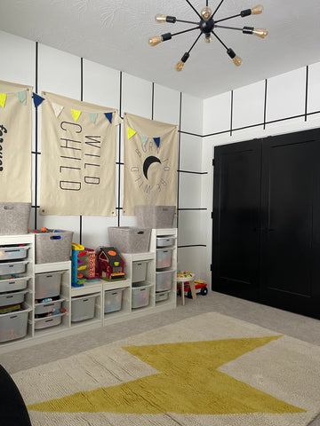 kids playroom with black and white grid walls, 3 canvas flags hanging on the wall, and a lightning bolt rug