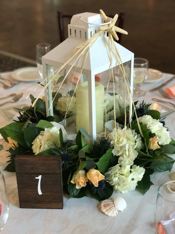 Lantern centerpieces with floral wreaths around done by Gig Morris Florist in Belmar, NJ at the Berkely Hotel in Asbury Park, NJ with hydrangea and seashells to make a seashore look.