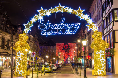 street view of Strasbourg with a sign that says Strasbourg under an archway of twinkling lights