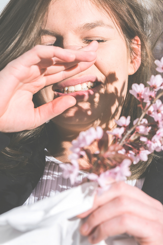 woman holding flowers while sneezing