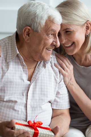 older couple hugging while he holds a gift