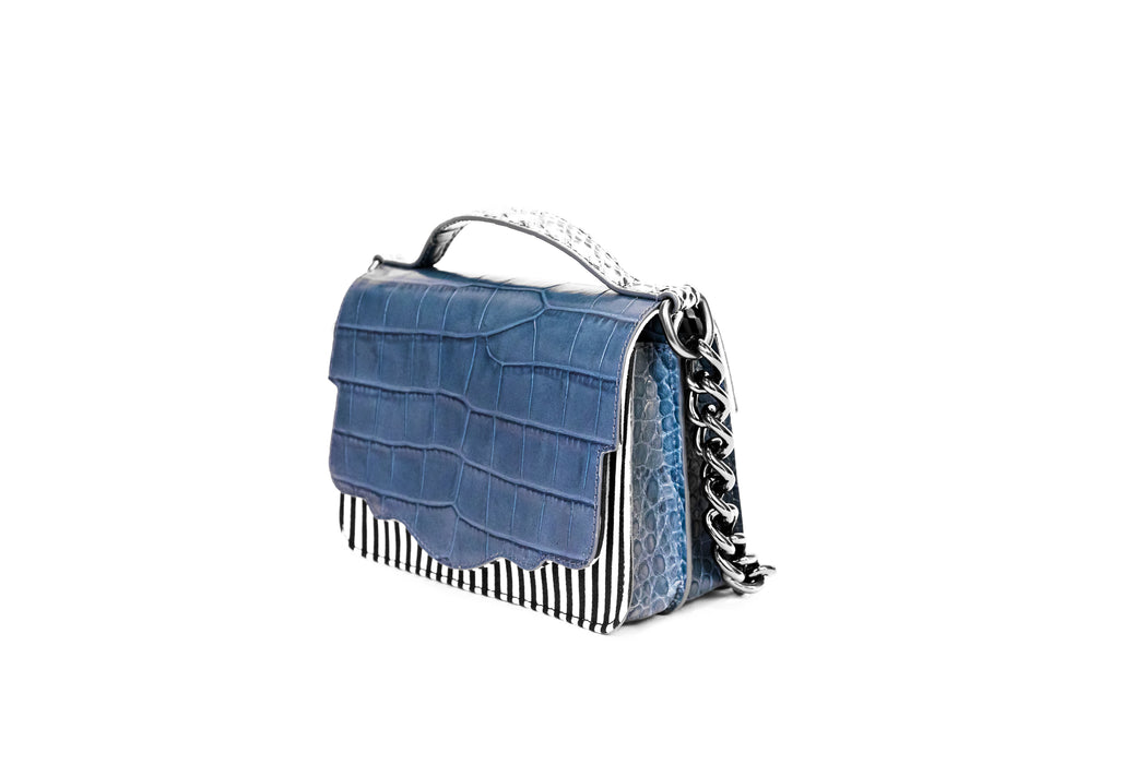 The double-sided Audreyette Mini in black and white striped canvas with denim blue embossed croc and black and white elaphe is a luxury handbag for every day. It's the same petite bag as the original Audreyette Mini, but with double the space. A designer crossbody bag that fits all the essentials. Can be worn as a crossbody or the strap can be doubled and worn on the shoulder. Elaphe top handle adds an extra dimension of texture.