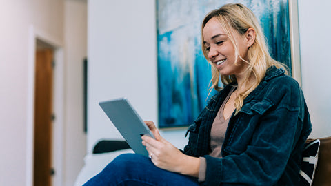 A smiling woman sits and reads. 