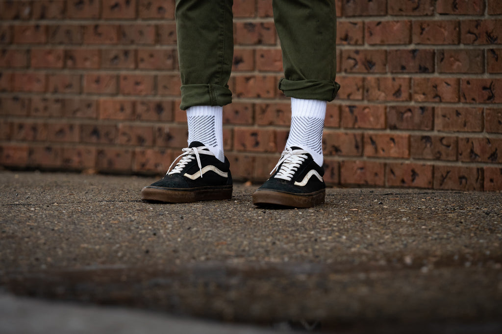Close up of man wearing suede sneakers, green trousers, and white Coolmax socks