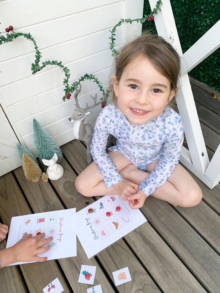 Little girl playing DIY festive bingo downloadable game wearing Willow Swim floral kids swimwear