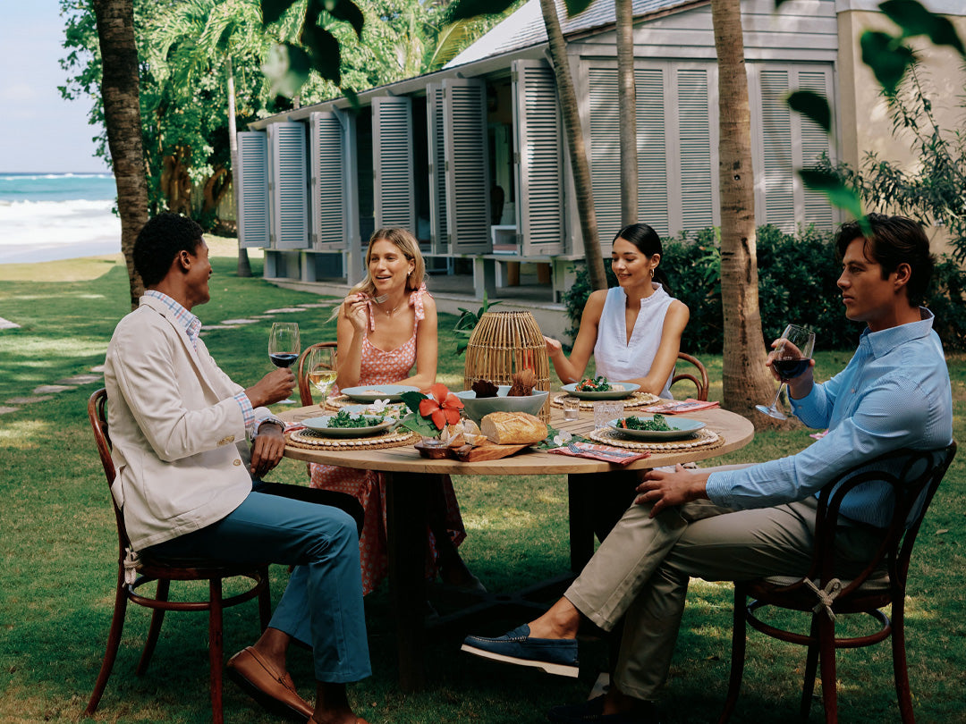 Group gathering in preppy, southern clothes outside in a garden by the ocean.