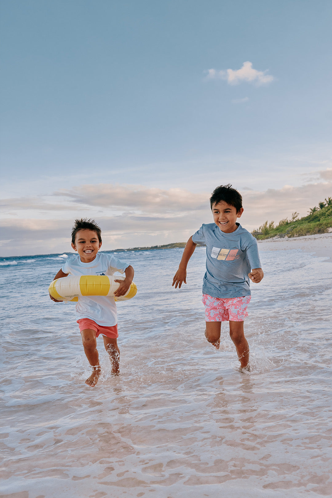 Two boys running down the beach in Southern Tide clothes for spring break.